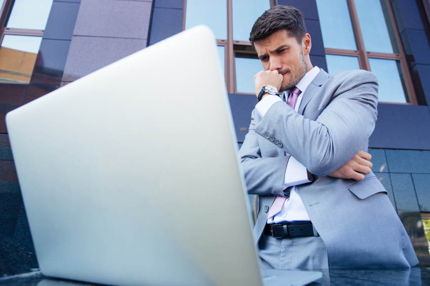 Portrait of a worried businessman looking at laptop outdoors