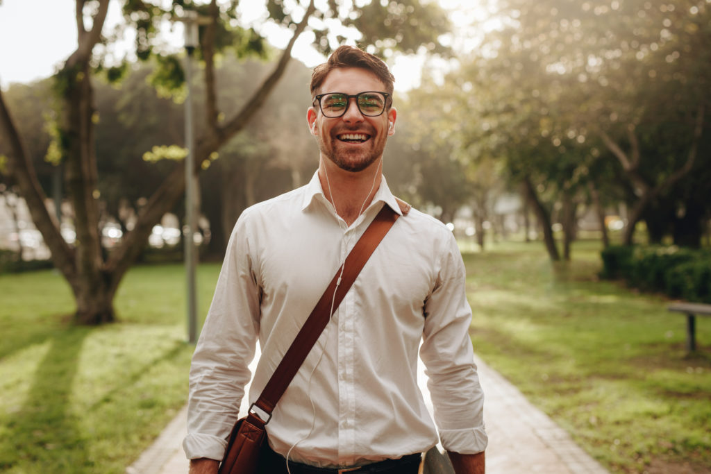 Cheerful businessman walking through a park going to office