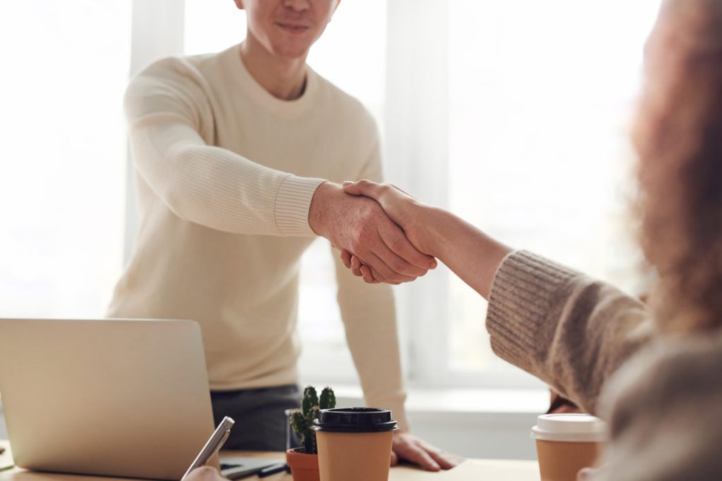 man and woman shaking hands across a table